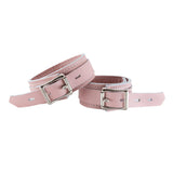 The Stupid Cute Wrist Cuffs are shown from the back fastened against a blank background. The leather is pink with white edges and white stitching on the borders. They have a silver D-Ring and fasten with a lockable buckle.