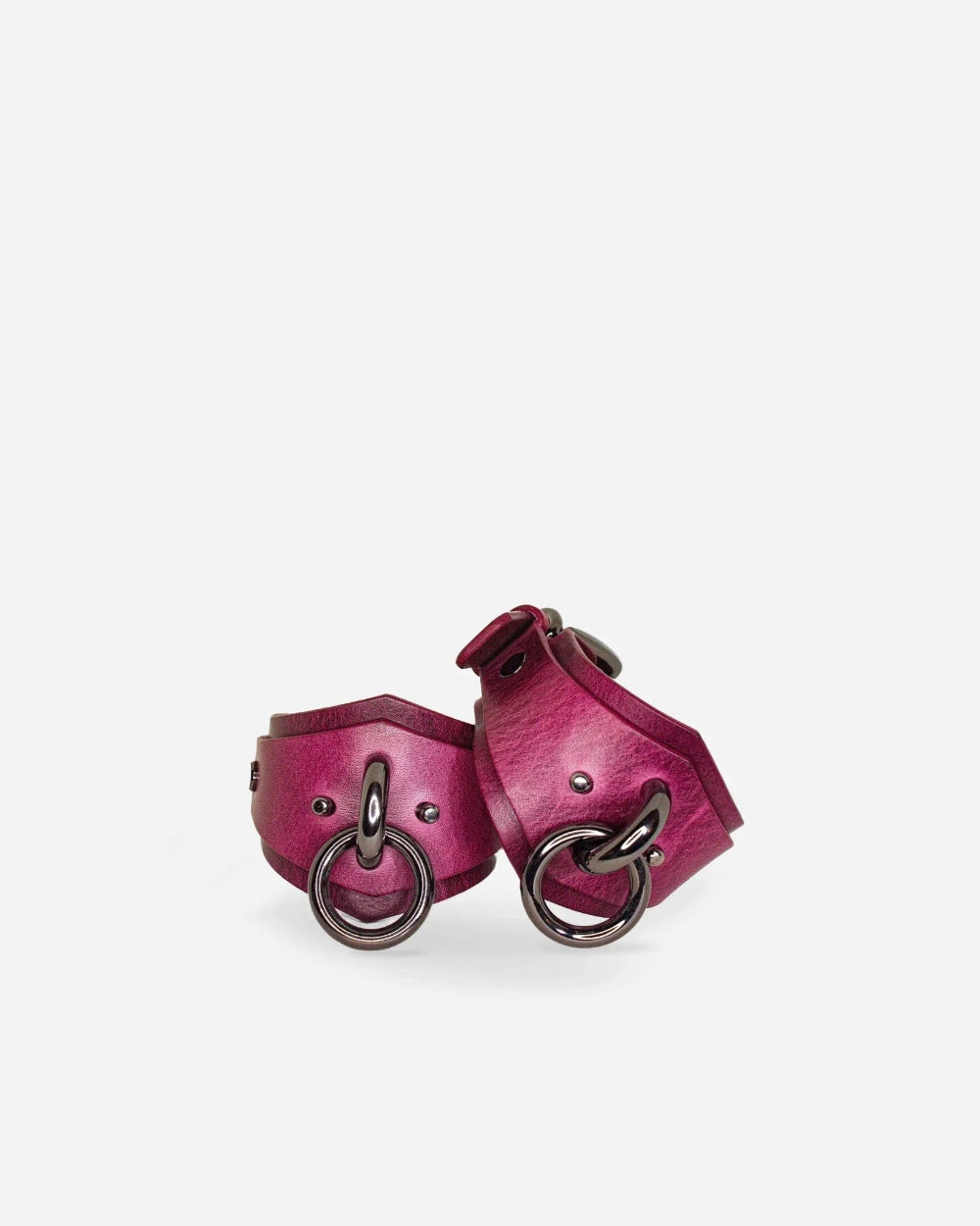 Pair of pink leather cuffs with metal rings on a white background